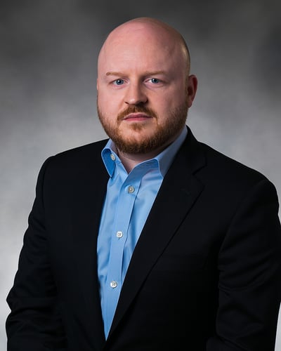 Dr. Womble smiling in front of a gray background.
