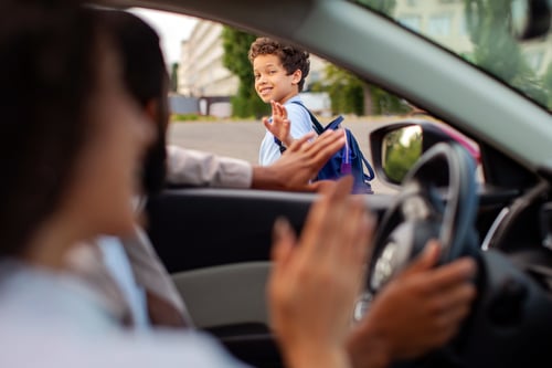 parents seeing their child off to school from the car