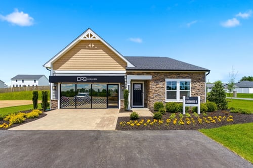 DRB Homes Edgewood II model home and sales center at Spring View Farms, featuring an attractive stone-accent exterior, inviting entryway, professionally landscaped grounds, and modern craftsman-style design under a bright blue sky.