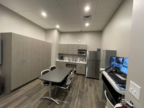 Clean and organized spa employee breakroom with kitchenette and administrative workstation.