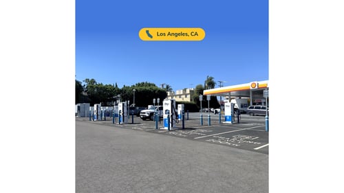 Several EVgo fast charging units installed in marked parking spaces at a public charging station, with EVgo logos on the chargers, protective bollards around each unit. CCS chargers featured in the image.