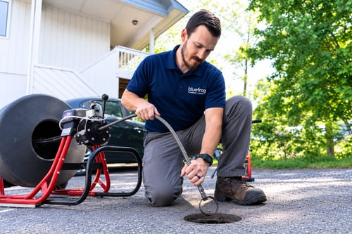 bluefrog plumber using professional drain cleaning equipment to clear a residential drain
