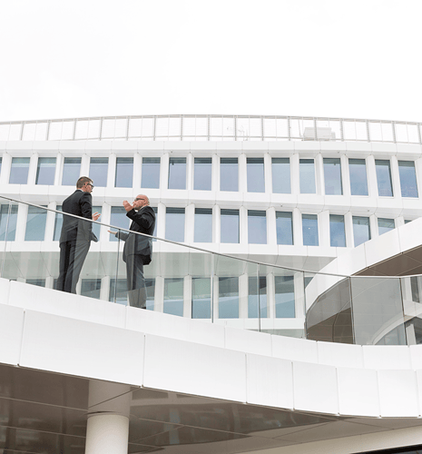 Two business men talking on a balcony.