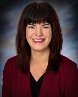 Keri smiling in front of a gray background.