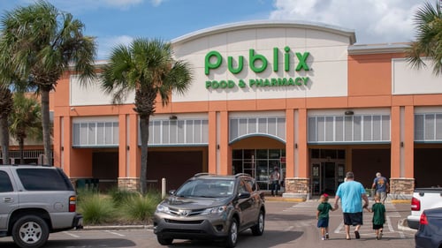 Adults and two children walking past cars towards entrance of Publix with palm trees