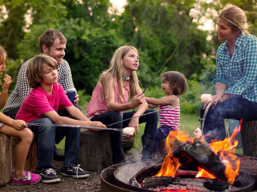 A family makes smores by a campfire