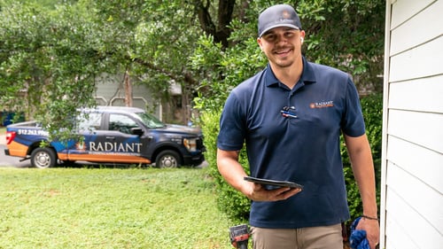 A Radiant technician standing on a porch with the work truck behind him