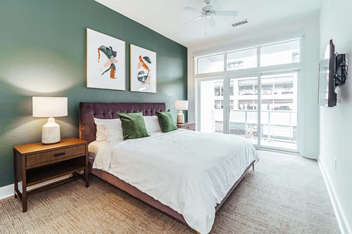 Bedroom with green accent wall and large windows at Reserve on 3rd Apartments, Birmingham, AL