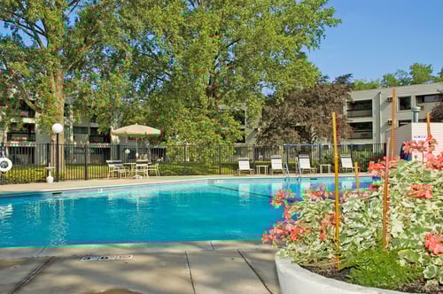 A swimming pool surrounded by trees and buildings at Hillsborough Apartments, Minnesota