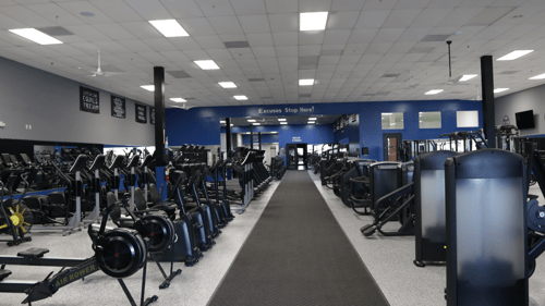 Cardio and strength training floor at Epic Health & Fitness Port Richey with treadmills, rowers, and free-weight stations.