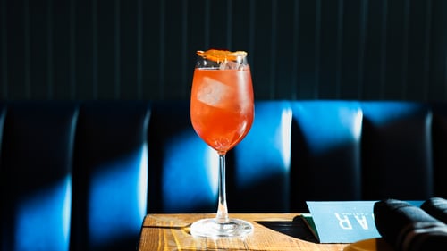 Red cocktail at el lugar cantina in front of blue booth.