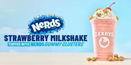 Zaxbys Strawberry Milkshake topped with whipped cream, NERDS candy, a cherry, and NERDS Gummy Clusters, alongside NERDS candy branding on a light blue background.