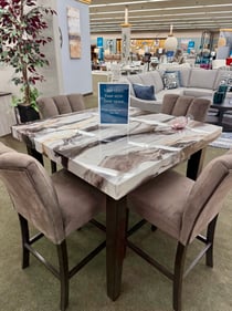 Modern counter-height marble-look dining table with four upholstered chairs on display at Slumberland Furniture Burlington. Shop stylish dining sets and home furniture in Burlington, Iowa.