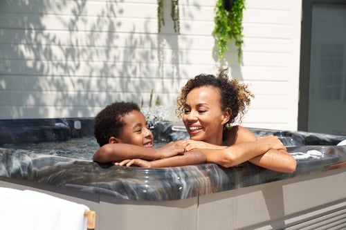 Caldera Vacanza hot tub in Midnight Canyon finish, family together in backyard installation