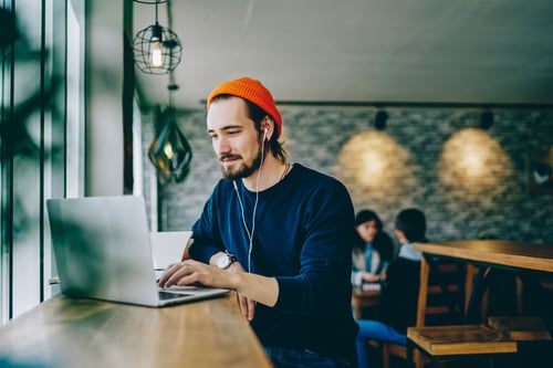 Man sitting at table typing on laptop in coffee shop