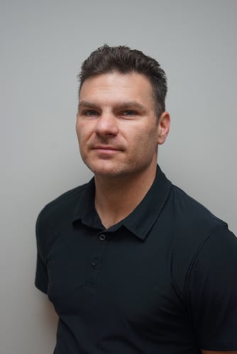 Agent Max Wilson standing and smiling wearing black t-shirt