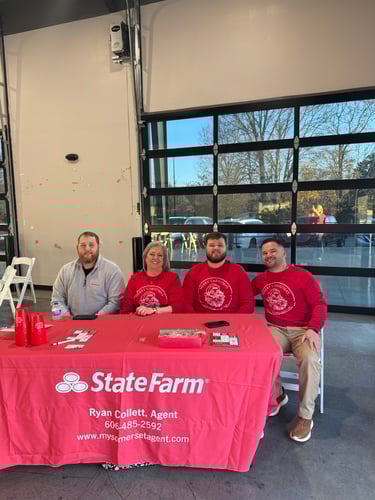Three men and one woman sitting at a table smiling.