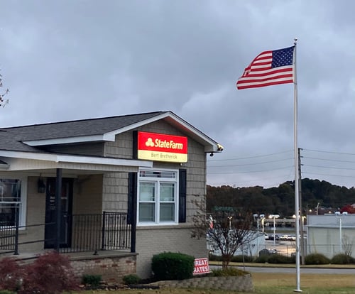 Brown building with black shutters and red State Farm sign out front