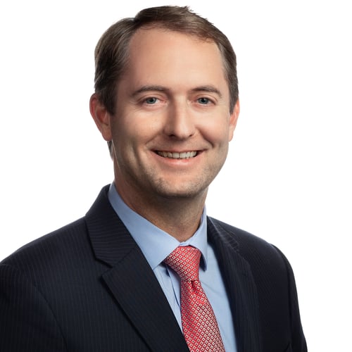 Headshot of Attorney Davis Rice in a black suit with a red tie smiling at the camera