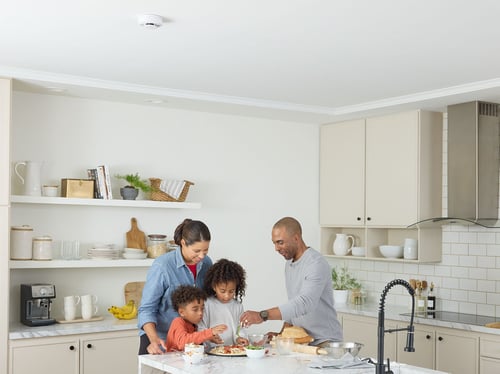 Family prepares dinner with a Kidde Combo alarm above them.