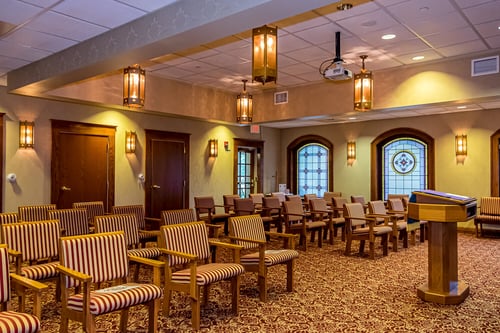 Well-lit event room with striped chairs, podium, and decorative lighting