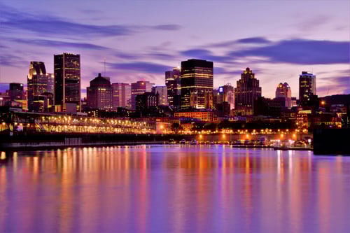 Montreal skyline at dusk with illuminated buildings reflecting on the St. Lawrence River