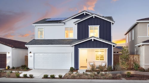 new two-story home at dusk with solar panels and white and navy exterior siding