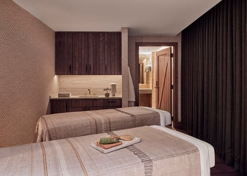 Couples treatment room with two massage tables and neutral tones