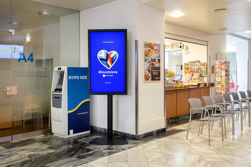 Schrägansicht des Bankomaten aus mittlerer Entfernung, die den gesamten Automaten und den umgebenden Bereich zeigt.