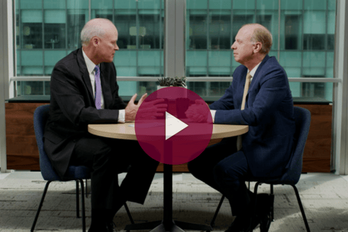 two men sitting at a table having a discussion