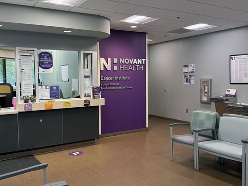 Patient reception desk with a purple wall that says Novant Health Cancer Institute.