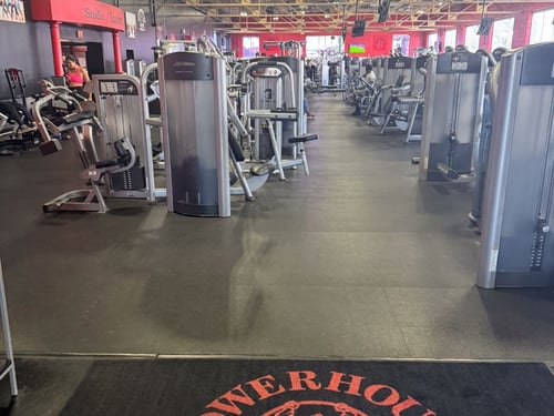 Spacious weight training area at a Powerhouse Gym in Linden featuring rows of Life Fitness strength machines, red and black decor, and high ceilings with exposed beams.