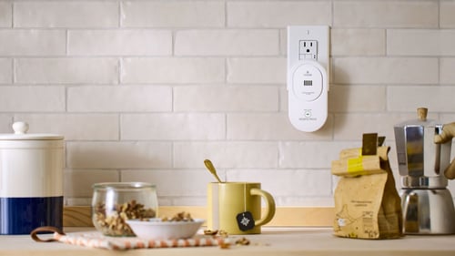 A CO alarm is plugged into an outlet in a kitchen