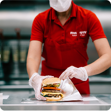 A collection of red uniformed restaurant crew members working and smiling.