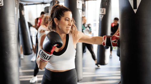 Woman practicing hitting the bag at a local TITLE Boxing Club gym.