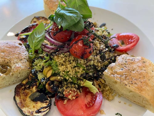 Freudenpracht Catering & Event Frankfurt - Frischer Quinoasalat mit gegrillten Auberginen, Kirschtomaten, Basilikum, Balsamico-Dressing und Oliven-Focaccia auf weißem Teller