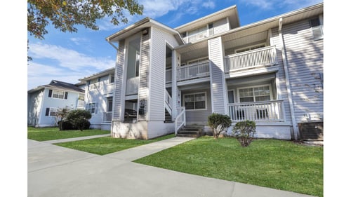 Apartment building with a white facade and a green lawn in front at Plantation Oaks Apartments in Savannah, GA, 31419