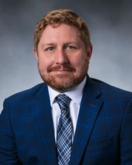 Dr. Ian Fekete smiling in front of a gray background.