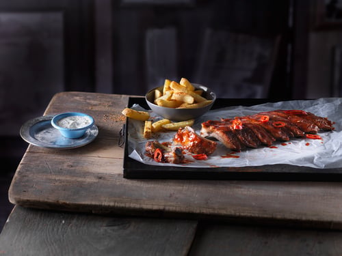 Platte mit Ribs und Pommes Frites daneben.