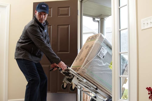 A Carrier dealer moves a furnace into a home as he performs an HVAC Installation