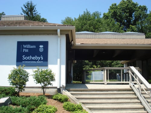 Modern white building with covered entrance housing William Pitt Sotheby's International Realty in Old Lyme, Connecticut, featuring landscaped grounds and stone steps.