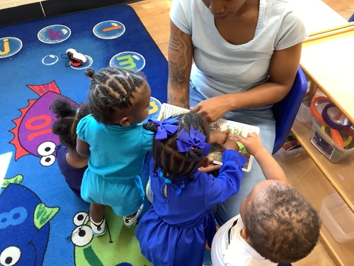 Teacher and children gathered around a keyboard, making music and having fun.