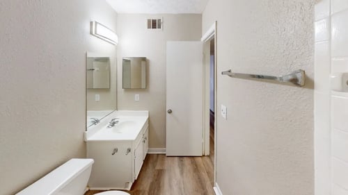 Bathroom with mirrors, toilet, and vanity at 2000 Oasis Apartments in Atlanta, Georgia 30316