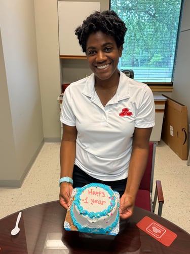 Team member Nicole holding a cake to celebrate her one-year work anniversary