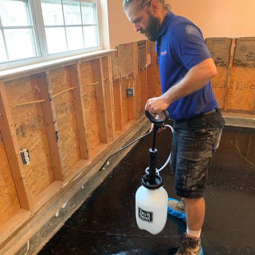 Tech spraying to prevent mold growth after water damage