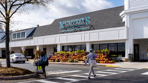 Pumpkin display and two people walking in front of McCaffrey's at Village at Newtown shopping center