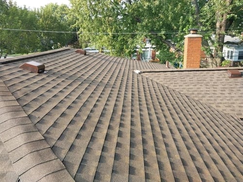 pictured of a roof with newly installed shingles form an aerial view in the sun