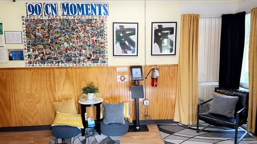 Bright and welcoming lobby with chairs for parents and a colorful bulletin board displaying cute moments from the daycare.