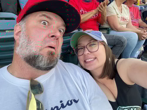 Agent Jessica Anderson and husband sitting in stands watching a baseball game making a funny face