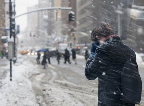 Woman walking in snow storm talking on cell phone